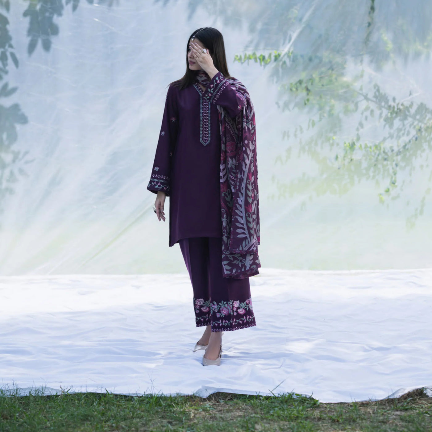 Woman wearing a purple embroidered outfit standing outdoors with a blurred natural background